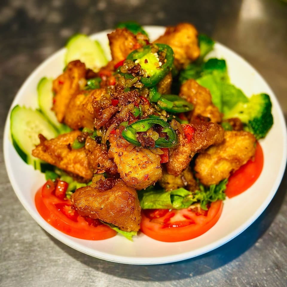 Blossom Vegan's spicy vegan chicken, garnished with jalapeños, cucumbers, and tomatoes.
