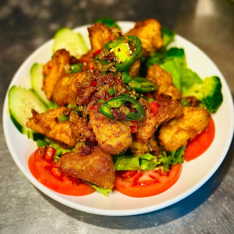 Blossom Vegan's spicy vegan chicken, garnished with jalapeños, cucumbers, and tomatoes.